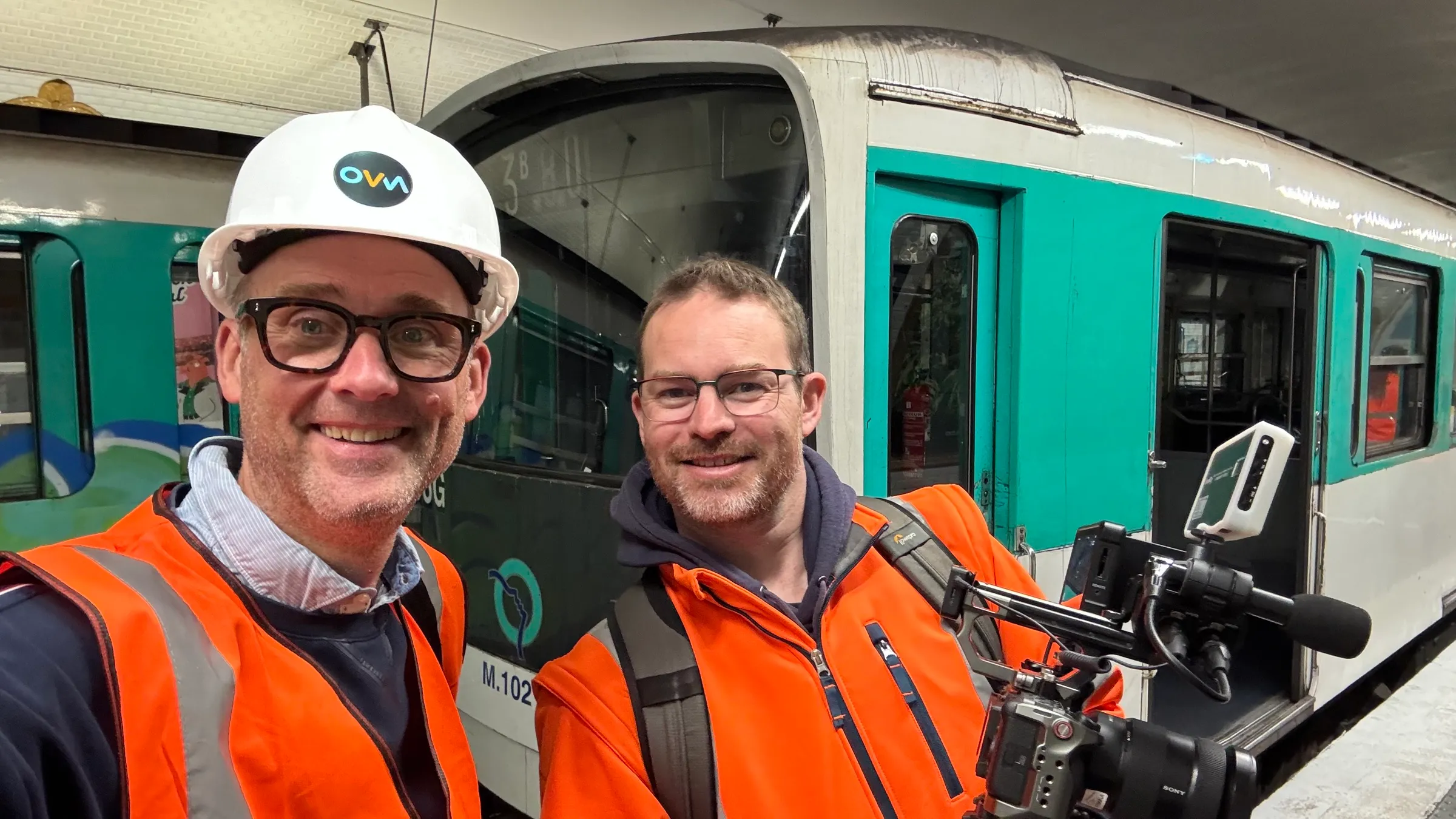 Olivier et Vincent, casque et gilet orange, sur un quai du métro parisien devant une rame à l'arrêt